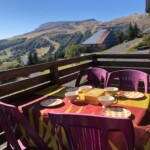 T3 Lamadalet à Super-Besse, zoom sur la terrasse avec vaisselle colorée et vue sur le massif du Sancy