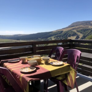 T3 Lamadalet à Super-Besse, zoom sur la terrasse avec vaisselle colorée et vue sur le massif du Sancy