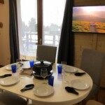 T3 Lamarmotte à Super-Besse, salle à manger avec appareil à raclette, télé 43" et terrasse avec vue sur la piscine enneigée